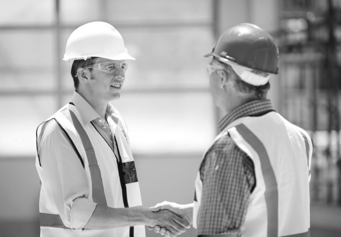 Two engineers shaking hands on a construction site